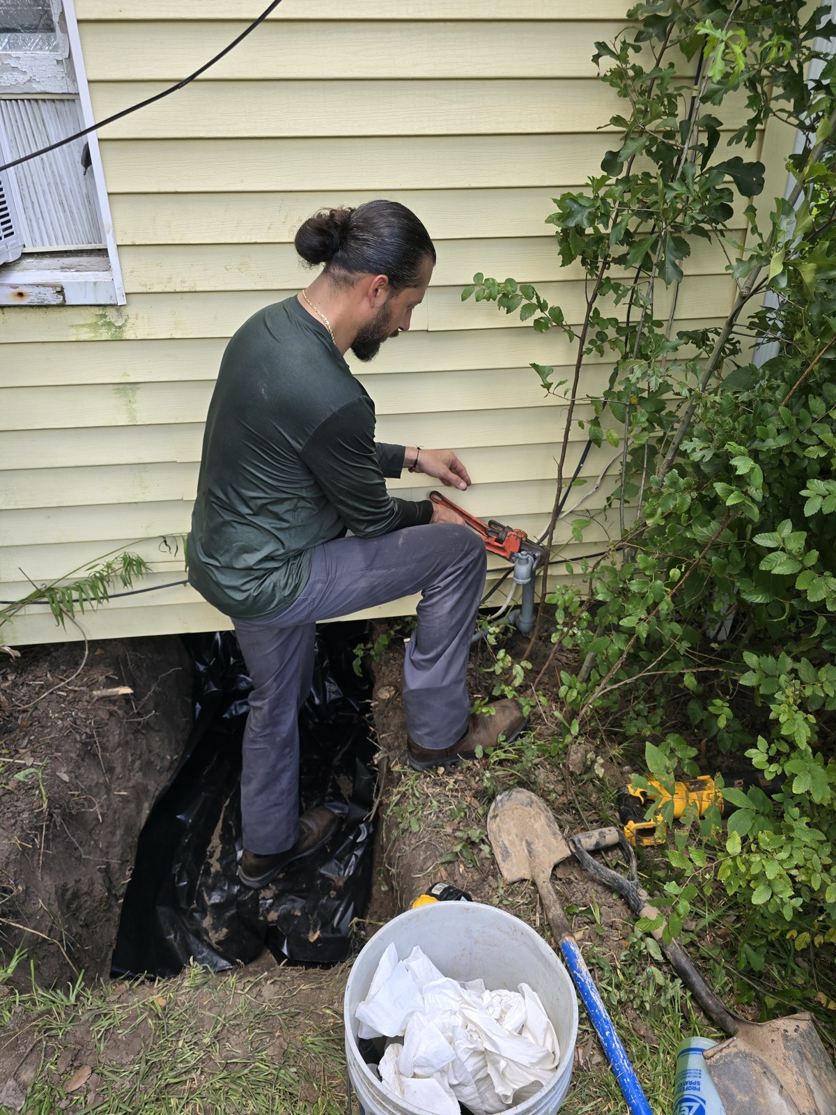 Jhonny working on outdoor plumbing with a pipe wrench